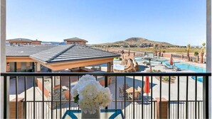 Hotel com área de piscina, incluindo hidromassagem e espreguiçadeiras, e vista para uma montanha ao fundo.
