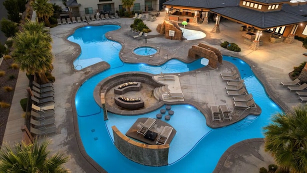Uma área de piscina com diversos elementos aquáticos, espreguiçadeiras e uma lareira.