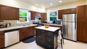 A modern kitchen with wooden cabinets, stainless steel appliances, and a large island.