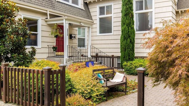 A residential property with a front porch, a wooden fence, and a bench.