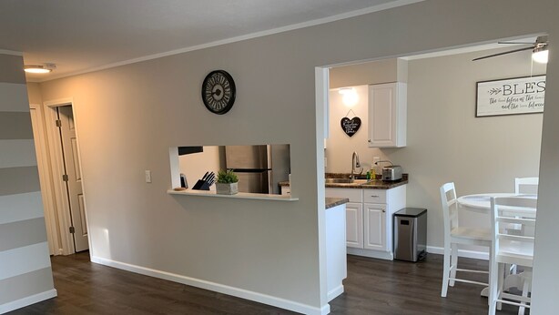 A modern kitchen with white cabinets, a stainless steel refrigerator, and a dining area with white chairs and a table.