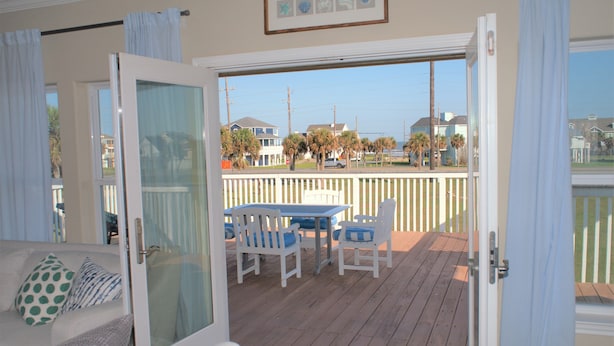 A room with a sliding glass door leading to an outdoor deck with a table and chairs.