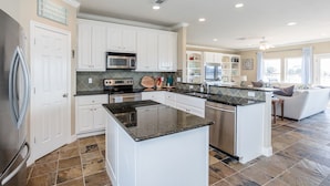 A modern kitchen with white cabinets, granite countertops, and stainless steel appliances.