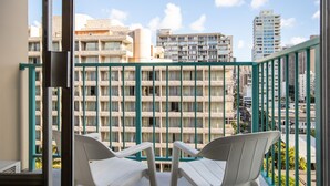 A balcony with white chairs, a view of a multi-story building with balconies, and a clear sky. - Aqua Aloha Surf Waikiki 1012 | Sparkling City Views – Pool & BBQ (Honolulu)