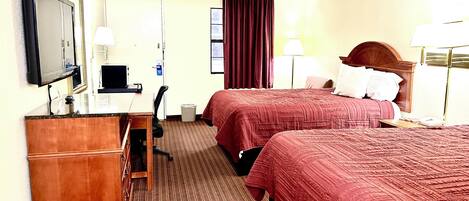 A hotel room with two beds, a desk, a chair, a TV, and a mirror.