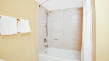 A bathroom with a bathtub, shower, and toilet.