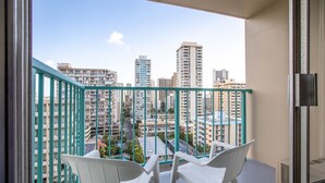 A balcony with white chairs, a table, and a view of high-rise buildings.