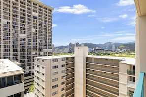 Un edificio de gran altura con varios balcones y vistas a un paisaje urbano y montañas distantes.