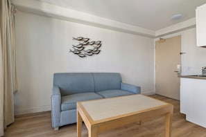Un salon avec un canapé bleu, une table en bois et une œuvre d’art abstraite accrochée au mur.