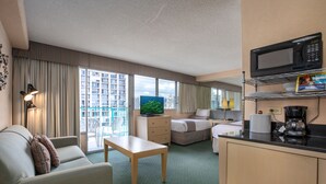 A hotel room with a bed, a desk, a TV, a coffee maker, and a view of the city.