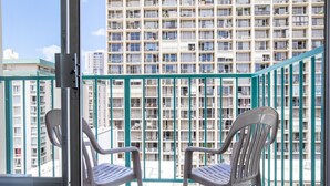 A balcony with two white plastic chairs, a metal railing, and a view of a high-rise building with multiple balconies. - Aqua Aloha Surf Waikiki 1408 | City View Suite – Pool & BBQ (Honolulu)