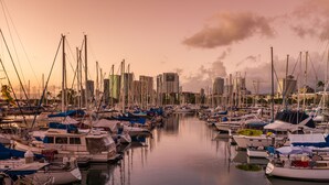 A marina with numerous boats docked, surrounded by tall buildings.
