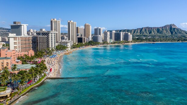 A coastal cityscape with a beach, high-rise buildings, and a mountain in the background.