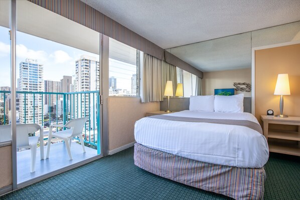 A hotel room with a large bed, a balcony with chairs, a city view, and a nightstand with a lamp. - Aqua Aloha Surf Waikiki 1512 | Sparkling City Views – Pool & BBQ (Honolulu)