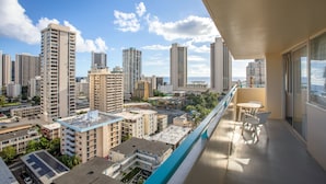 Un balcón con vistas a un paisaje urbano, incluyendo edificios altos y un cielo despejado.