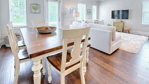 A spacious living area with a dining table and chairs, a sofa, a TV, and a ceiling fan. - Shore Do Love You: 5BR, Sleeps 12, Heated Private Pool & Optional Hot Tub! (Santa Rosa Beach)