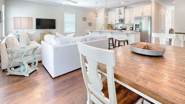 A modern kitchen with white cabinetry, a wooden dining table, and a built-in oven. - Shore Do Love You: 5BR, Sleeps 12, Heated Private Pool & Optional Hot Tub! (Santa Rosa Beach)