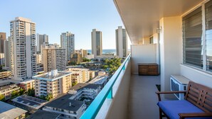 A balcony with a view of a cityscape, including high-rise buildings and a body of water.