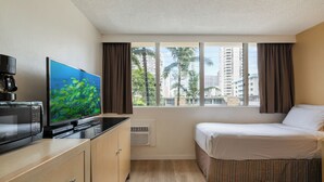 A hotel room with a bed, a TV, a microwave, and a window with curtains. - Aqua Aloha Surf Waikiki 201 | Sparkling City Views – Pool & BBQ (Honolulu)