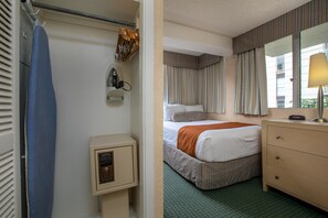 Et hotelværelse med seng, kommode, spejl og et vindue med gardiner.