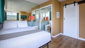 Habitación de hotel con una cama grande, un armario correderas y vistas a la ciudad.