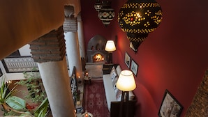 A cozy interior with a fireplace, red walls, and hanging lamps. - Chambre Tahmera (Marrakech)
