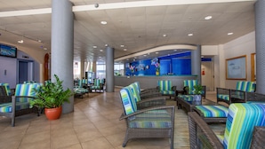 A lobby with wicker furniture, potted plants, and a reception desk. - Aqua Aloha Surf Waikiki 609 | Sparkling City Views – Pool & BBQ (Honolulu)