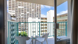 Un balcon avec des chaises blanches et une vue sur un immeuble de grande hauteur.