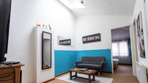 Ein gemütliches Zimmer mit einer Couch, einem kleinen Tisch, einem Spiegel und einem Bett im Hintergrund.