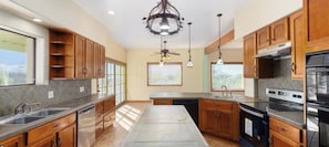 A kitchen with wooden cabinets, a central island, a stove, and a ceiling fan.