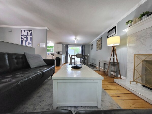 Una sala de estar moderna con un sofá de cuero negro, una mesa de centro blanca y una chimenea.
