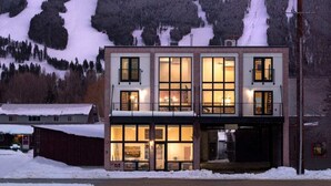 En toetages bygning med store vinduer, en balkon og udsigt til et snøbeklædt bjerg.