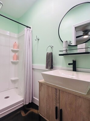 Une salle de bain avec une douche, un lavabo et un miroir.
