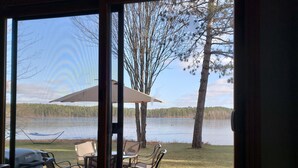 A patio with outdoor furniture, a grill, and a view of a lake and forest. - Perfect Northwoods Retreat (tomahawk)