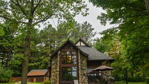 A stone and wood cabin with a large window and a patio area. - Perfect Northwoods Retreat (tomahawk)