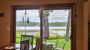 A dining area with a table and chairs, a view of a lake, and a door leading outside. - Perfect Northwoods Retreat (tomahawk)
