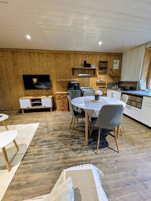 Une cuisine moderne avec des murs en bois, une table à manger avec des chaises, un téléviseur et une cuisinière.