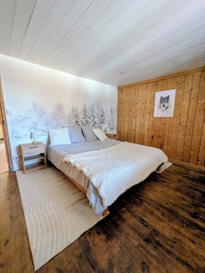 A bedroom with a bed, a nightstand, a wall mural, and wooden paneling.
