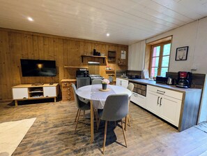 Een knus keuken met houten wanden, een eettafel met stoelen, een flatscreen televisie en een koffiezetapparaat.
