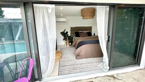 A bedroom with a bed, bedside table, lamp, and potted plants. - Ohhh-Our sweet little surprise #TinyPoolHouse #MiamiDesignDistrict (Miami)