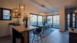 A modern kitchen with a central island, pendant lighting, and large windows providing natural light.