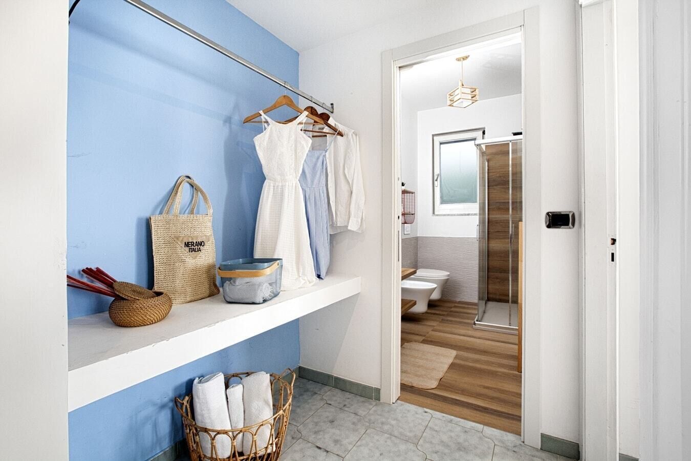 Un baño con piso de madera, un lavamanos blanco y una cabina de ducha de vidrio.