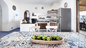 Una cocina moderna con azulejos blancos, una isla central y un comedor con mantel estampado.