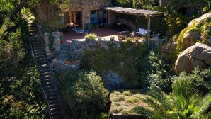 Un bâtiment en pierre doté d’un patio, entouré d’une végétation luxuriante et agrémenté d’un escalier en pierre.