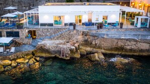 A waterfront hotel with outdoor seating, a pool, and a staircase leading to the upper levels.