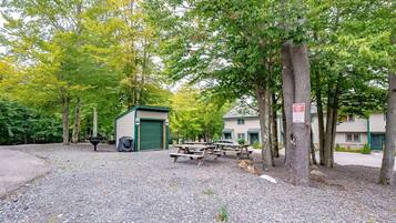 A campground with picnic tables, a shed, and a building with a green door.