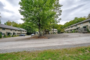 A residential area with multiple two-story houses, a gravel driveway, and a large tree in the center.