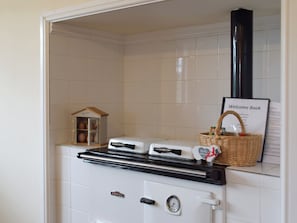 Un coin cuisine équipé d’une cuisinière, une maquette de maison et un livre d’accueil.