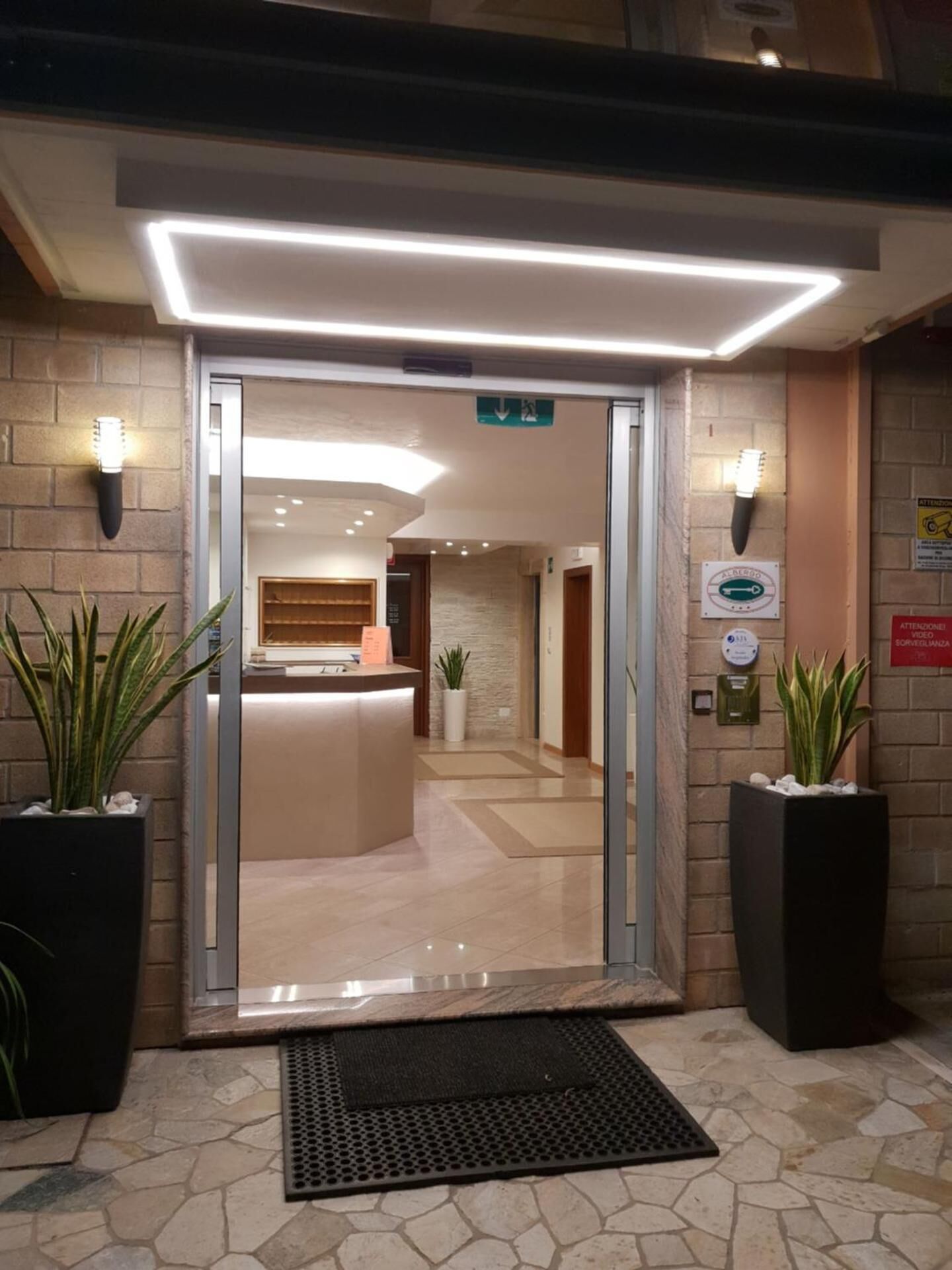 A reception area with a glass door, a reception desk, and potted plants.