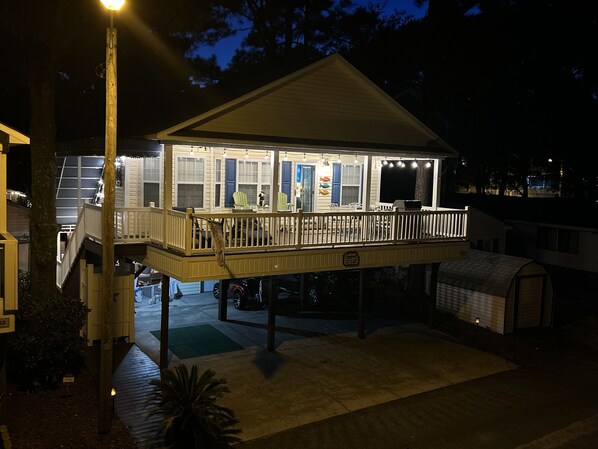 A waterfront house with a covered deck, outdoor seating, and a garage.